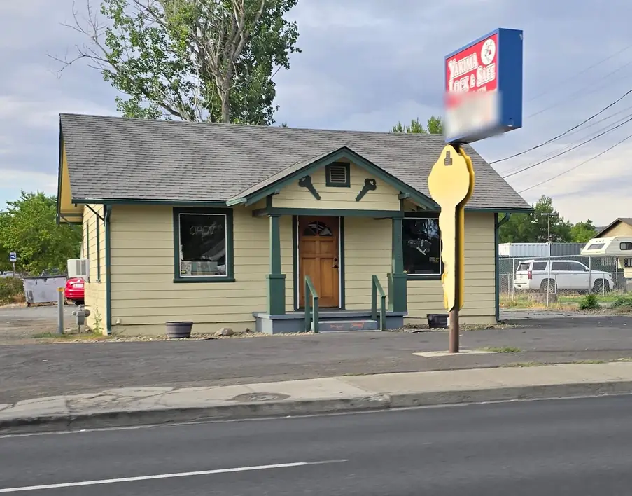 The Yakima Lock & Safe bungalow on a summer evening, green trim, wooden door and the giant yellow key on its pole