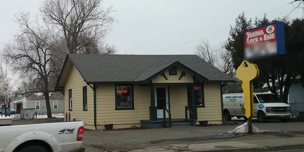 Yakima Lock & Safe in winter: OPEN signs lit in both windows, the lettered work van parked beside the giant yellow key